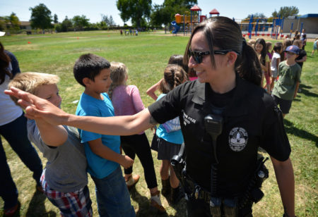 Fullerton PD Cpl. Gaby Soto gives kids high-fives at the conclusion of a Team Kids assembly as Fullerton Police and Fire Departments pay a visit to Rolling Hills Elementary School. Photo by Steven Georges/Behind the Badge OC
